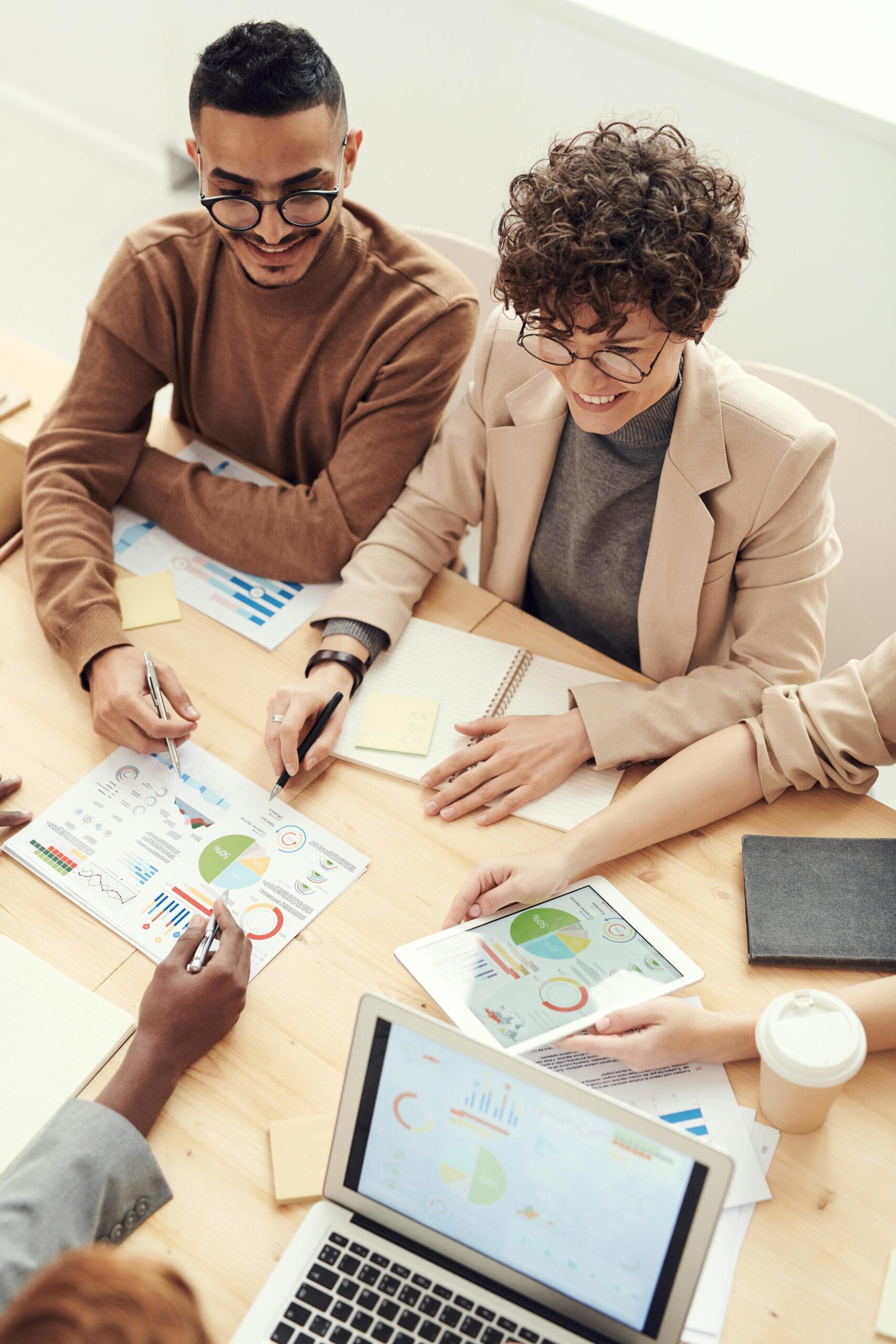 Teilnehmer des Business Coach Lehrgangs arbeiten zusammen mit anderen Teilnehmern an einem Tisch